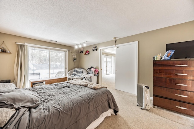 carpeted bedroom featuring a textured ceiling and rail lighting