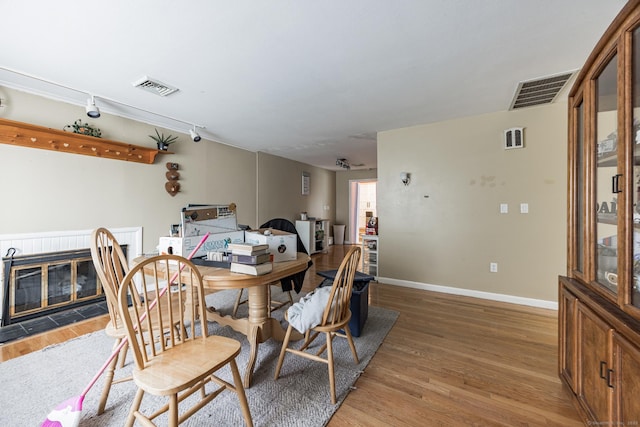 dining space with hardwood / wood-style floors, rail lighting, and a tile fireplace