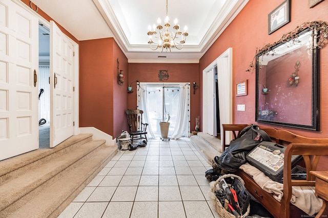 tiled foyer with an inviting chandelier, crown molding, and a tray ceiling