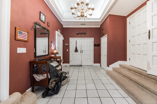 entrance foyer featuring a raised ceiling, light tile patterned flooring, ornamental molding, and a notable chandelier