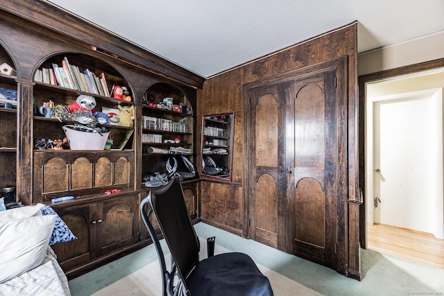 office area with wood walls, light colored carpet, and built in features