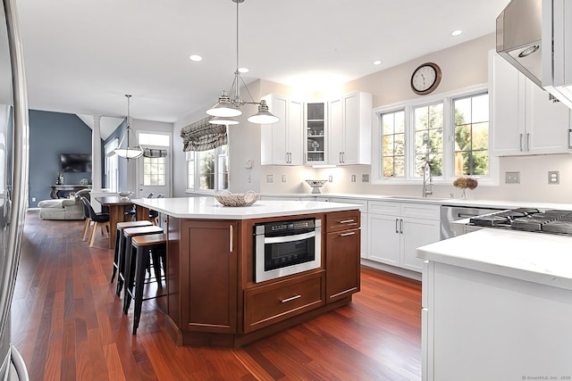 kitchen with pendant lighting, white cabinetry, a kitchen island, and stainless steel oven