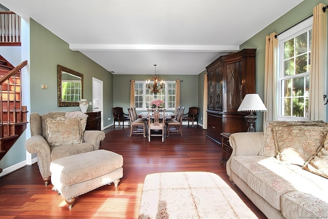 living room with beam ceiling, dark wood-type flooring, and an inviting chandelier