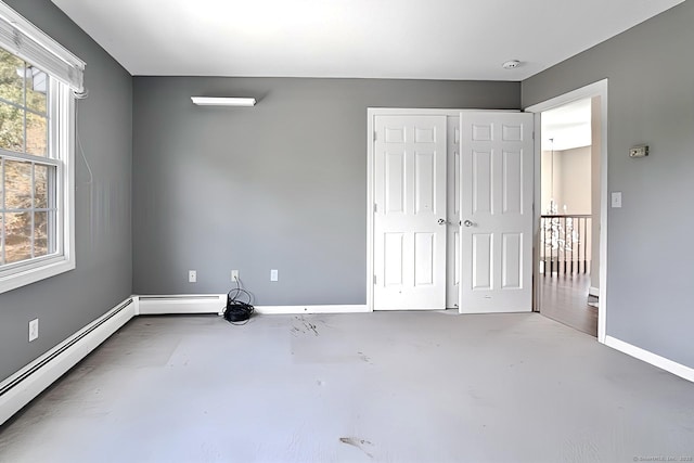 unfurnished room featuring a wealth of natural light, concrete flooring, and a baseboard heating unit