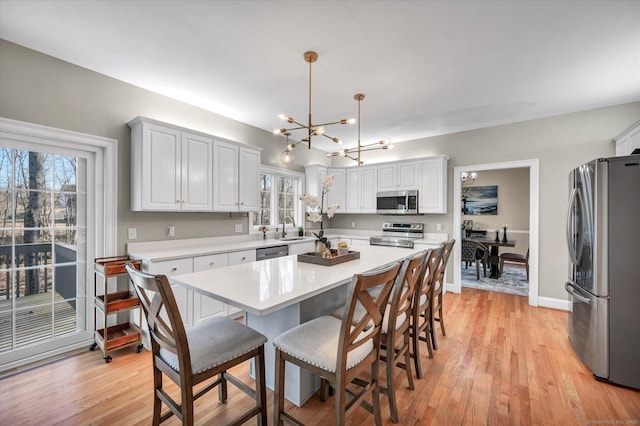 kitchen featuring white cabinets, sink, stainless steel appliances, and hanging light fixtures