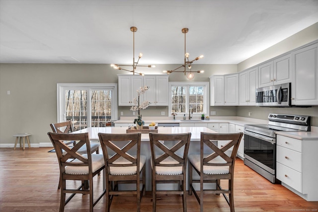 kitchen featuring a center island, white cabinetry, stainless steel appliances, and hanging light fixtures