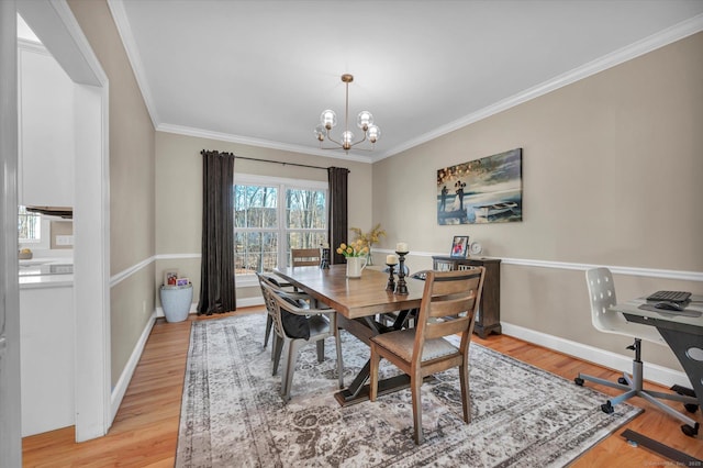 dining area featuring crown molding, light wood-type flooring, and a notable chandelier