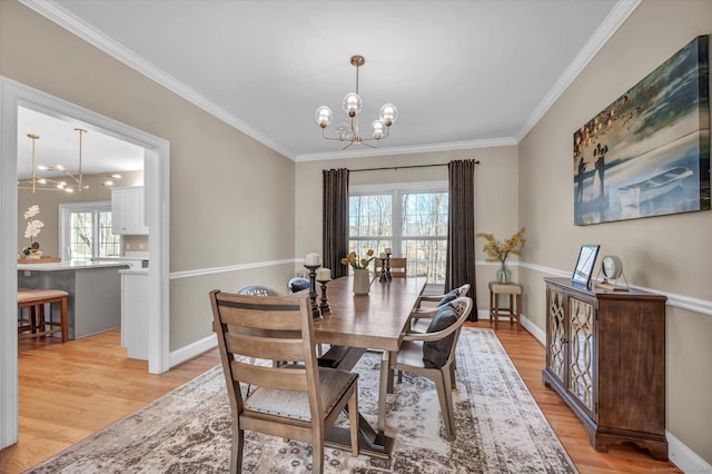 dining space featuring light hardwood / wood-style floors, crown molding, and an inviting chandelier