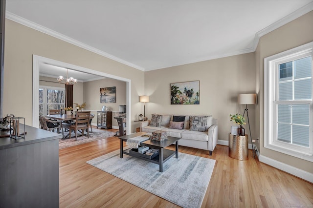 living room featuring light hardwood / wood-style flooring, crown molding, and a notable chandelier