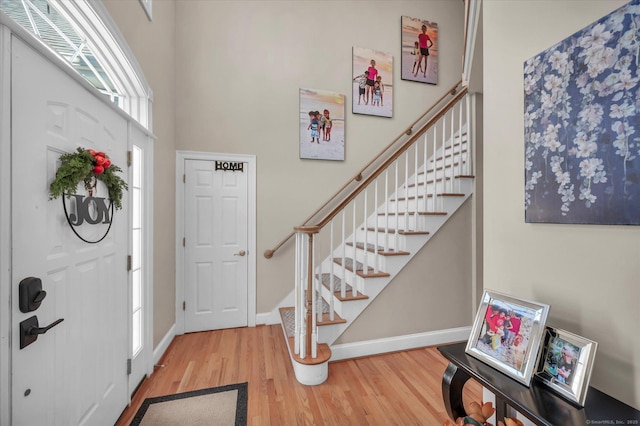 entryway featuring a towering ceiling and wood-type flooring