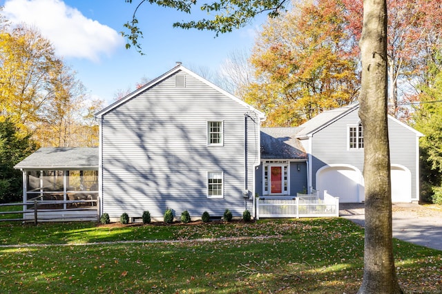 view of side of property with a yard, a sunroom, and a garage