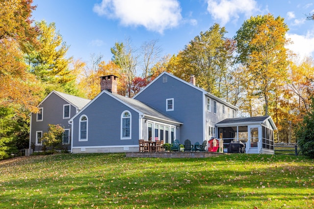 back of property featuring a lawn, a sunroom, and a patio area