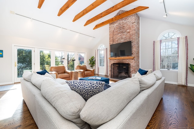 living room featuring dark hardwood / wood-style floors, vaulted ceiling with beams, track lighting, and a fireplace