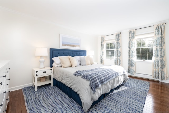 bedroom with dark hardwood / wood-style flooring, a baseboard heating unit, and ornamental molding