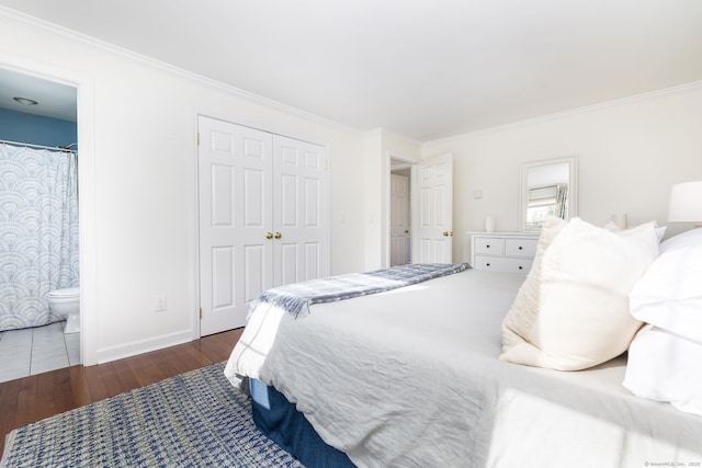 bedroom featuring dark wood-type flooring, ensuite bath, crown molding, and a closet