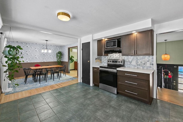 kitchen with tasteful backsplash, dark brown cabinetry, an inviting chandelier, pendant lighting, and stainless steel appliances