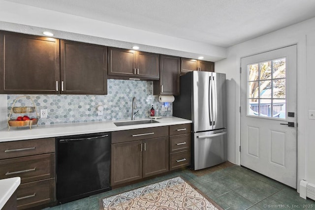 kitchen with black dishwasher, decorative backsplash, sink, dark brown cabinetry, and stainless steel fridge