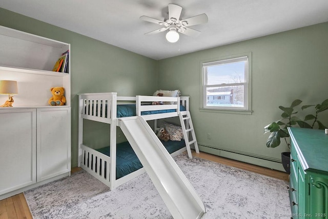 bedroom featuring light wood-type flooring, ceiling fan, and a baseboard radiator