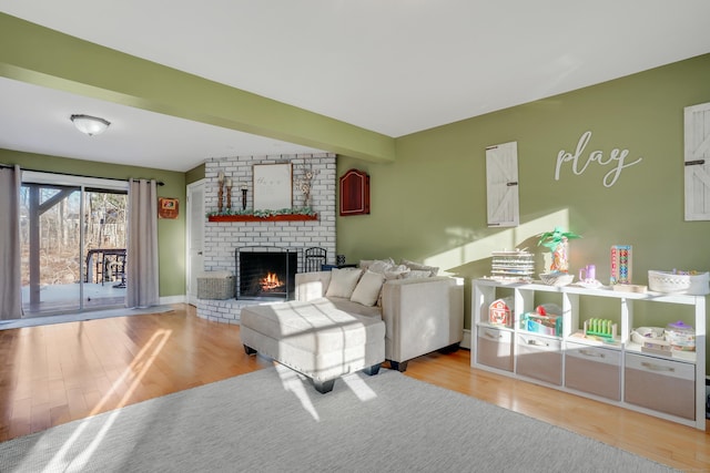 living room featuring a fireplace, beamed ceiling, and light hardwood / wood-style flooring