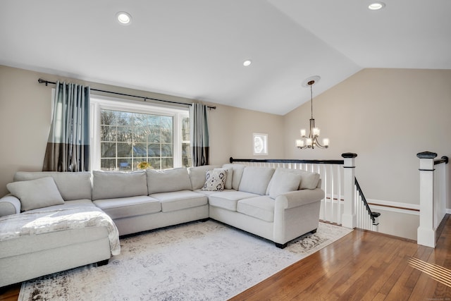 living room featuring an inviting chandelier, wood-type flooring, and vaulted ceiling