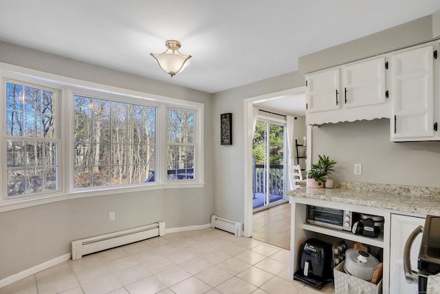 kitchen featuring light stone counters, white cabinetry, light tile patterned floors, and a baseboard radiator