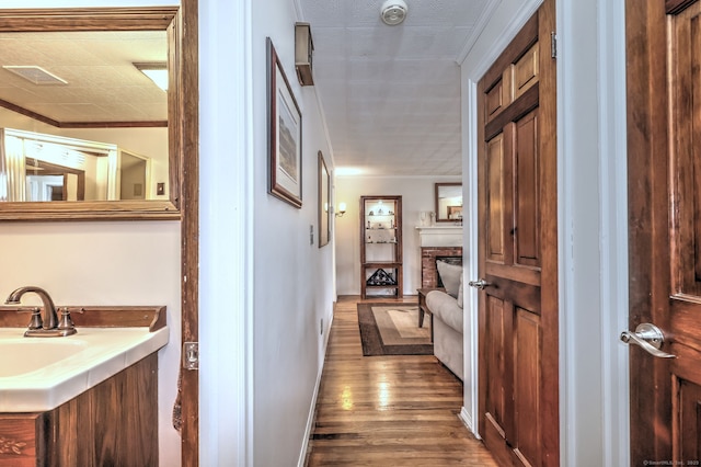 corridor with crown molding, sink, and hardwood / wood-style flooring