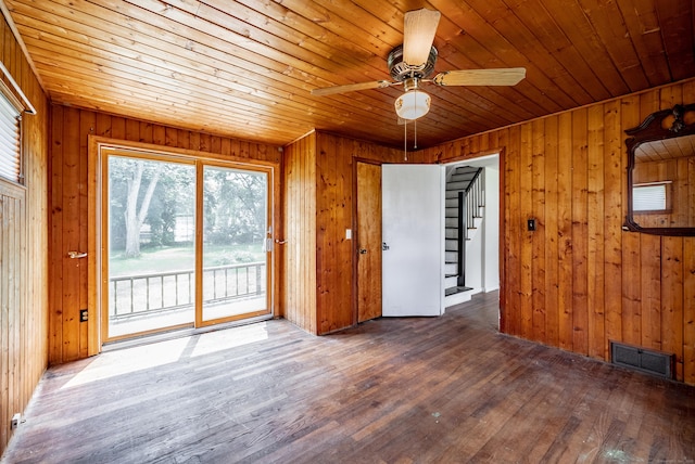 spare room with ceiling fan, dark hardwood / wood-style flooring, wood ceiling, and wooden walls