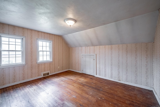 additional living space with hardwood / wood-style floors and lofted ceiling