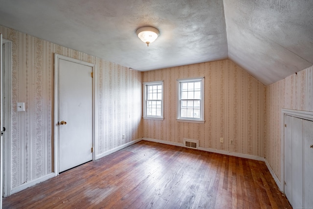 bonus room featuring wood-type flooring, a textured ceiling, and vaulted ceiling