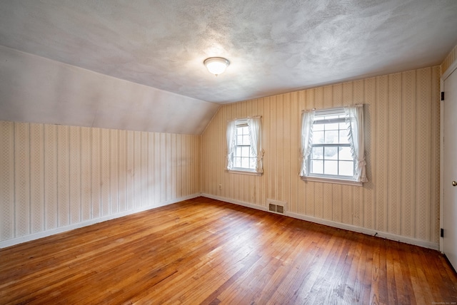 bonus room with light wood-type flooring and lofted ceiling