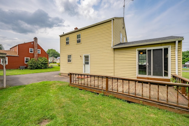 rear view of property featuring a lawn, cooling unit, and a deck