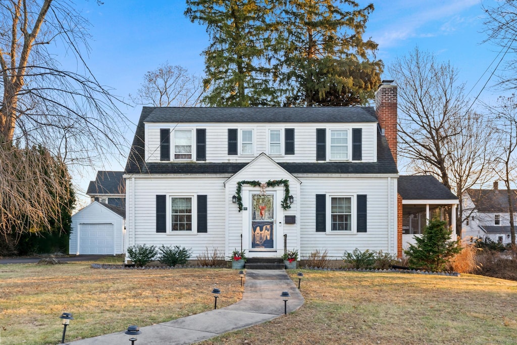 view of front facade with a front lawn, an outdoor structure, and a garage