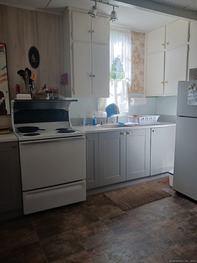 kitchen with stainless steel fridge, sink, white cabinetry, and white stove