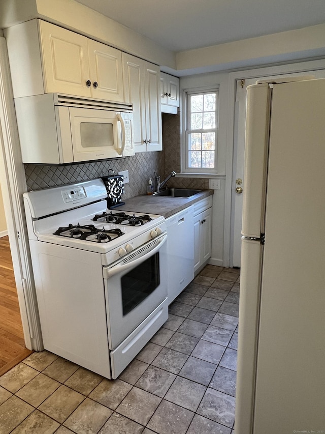 kitchen with sink, light tile patterned floors, tasteful backsplash, white appliances, and white cabinets