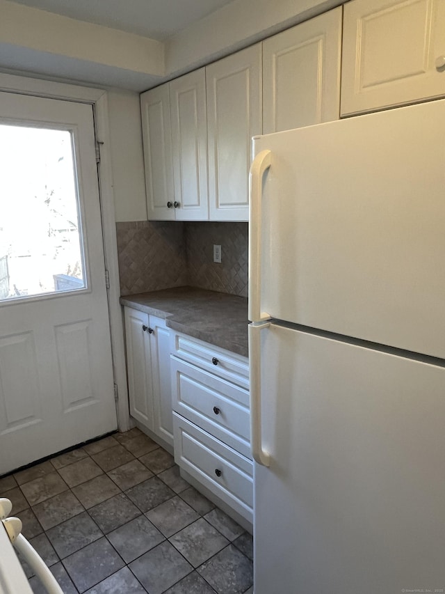 kitchen with tasteful backsplash, white cabinetry, white fridge, and light tile patterned floors