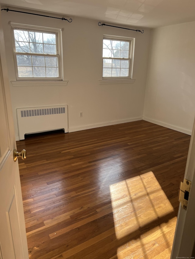 spare room featuring plenty of natural light, dark hardwood / wood-style flooring, and radiator