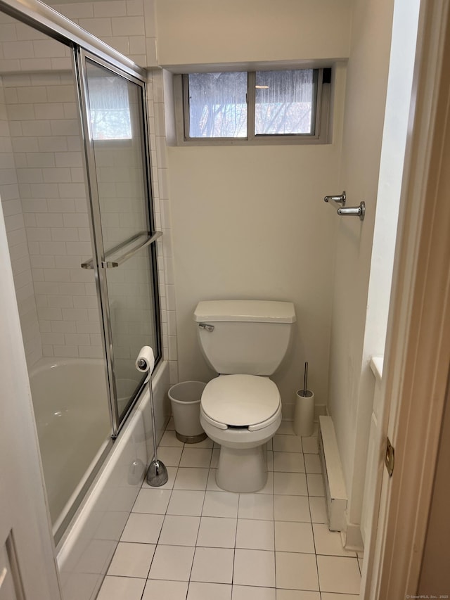 bathroom with tile patterned floors, toilet, and bath / shower combo with glass door