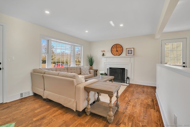 living room featuring beamed ceiling, hardwood / wood-style flooring, and a fireplace