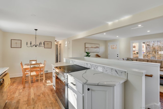 kitchen with pendant lighting, an inviting chandelier, light hardwood / wood-style flooring, high end stove, and white cabinetry