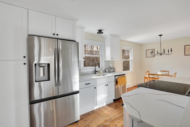 kitchen featuring decorative light fixtures, light stone counters, white cabinetry, and stainless steel appliances