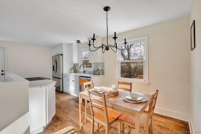 dining room featuring sink, plenty of natural light, light hardwood / wood-style flooring, and an inviting chandelier