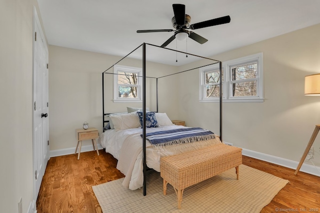 bedroom featuring multiple windows, hardwood / wood-style flooring, and ceiling fan