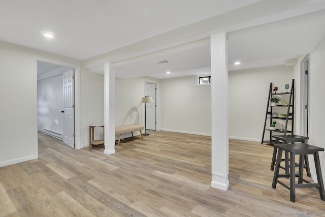 basement featuring light hardwood / wood-style floors and a baseboard radiator