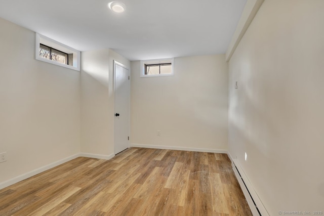 basement featuring a baseboard radiator and light hardwood / wood-style flooring