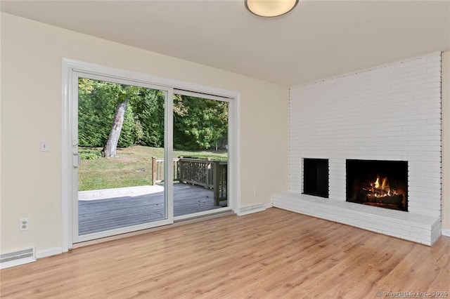 unfurnished living room featuring a fireplace and light hardwood / wood-style floors