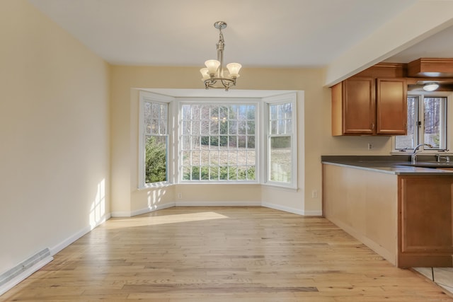 unfurnished dining area featuring light hardwood / wood-style flooring, a notable chandelier, and sink