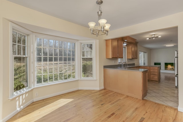 kitchen with kitchen peninsula, pendant lighting, light wood-type flooring, and plenty of natural light