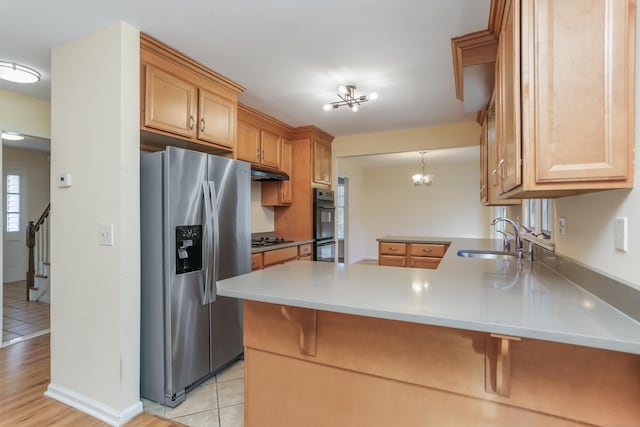 kitchen featuring sink, kitchen peninsula, pendant lighting, a chandelier, and appliances with stainless steel finishes