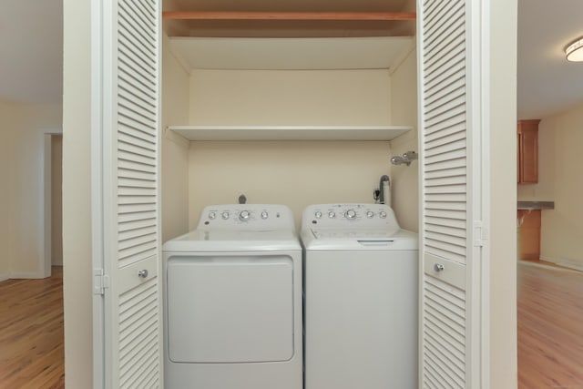 laundry area with washer and clothes dryer and light wood-type flooring