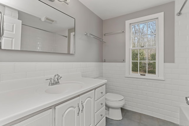 bathroom with vanity, toilet, tile walls, and walk in shower